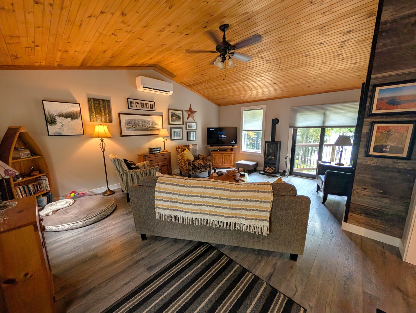 A grey couch with a blanket draped over the back faces chairs and a TV in a living room