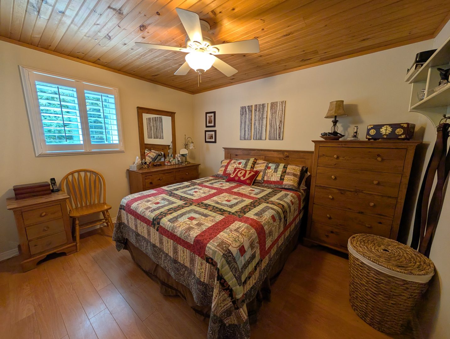 A bed with a red and white plaid bedspread in a white bedroom