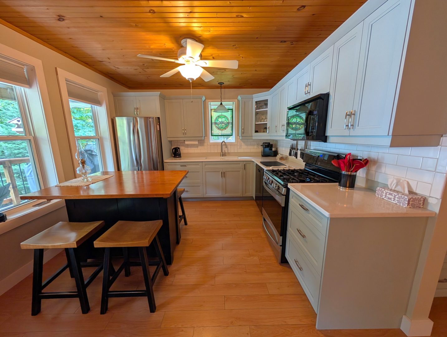 A white kitchen with a square wood dining table to the left