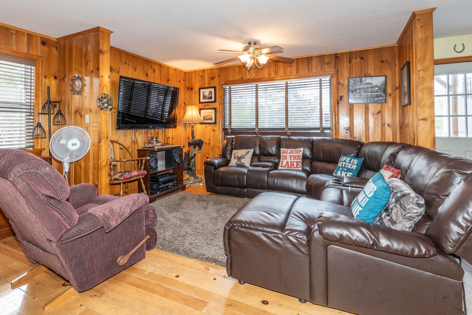 Brown leather couches face each other in a wood-paneled room