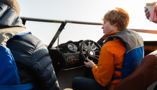 A red-headed boy driving a boat