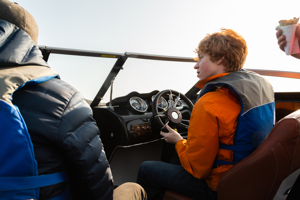 A red-headed boy driving a boat
