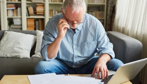 Older man at the laptop computer doing the bookkeeping or preparing the tax return