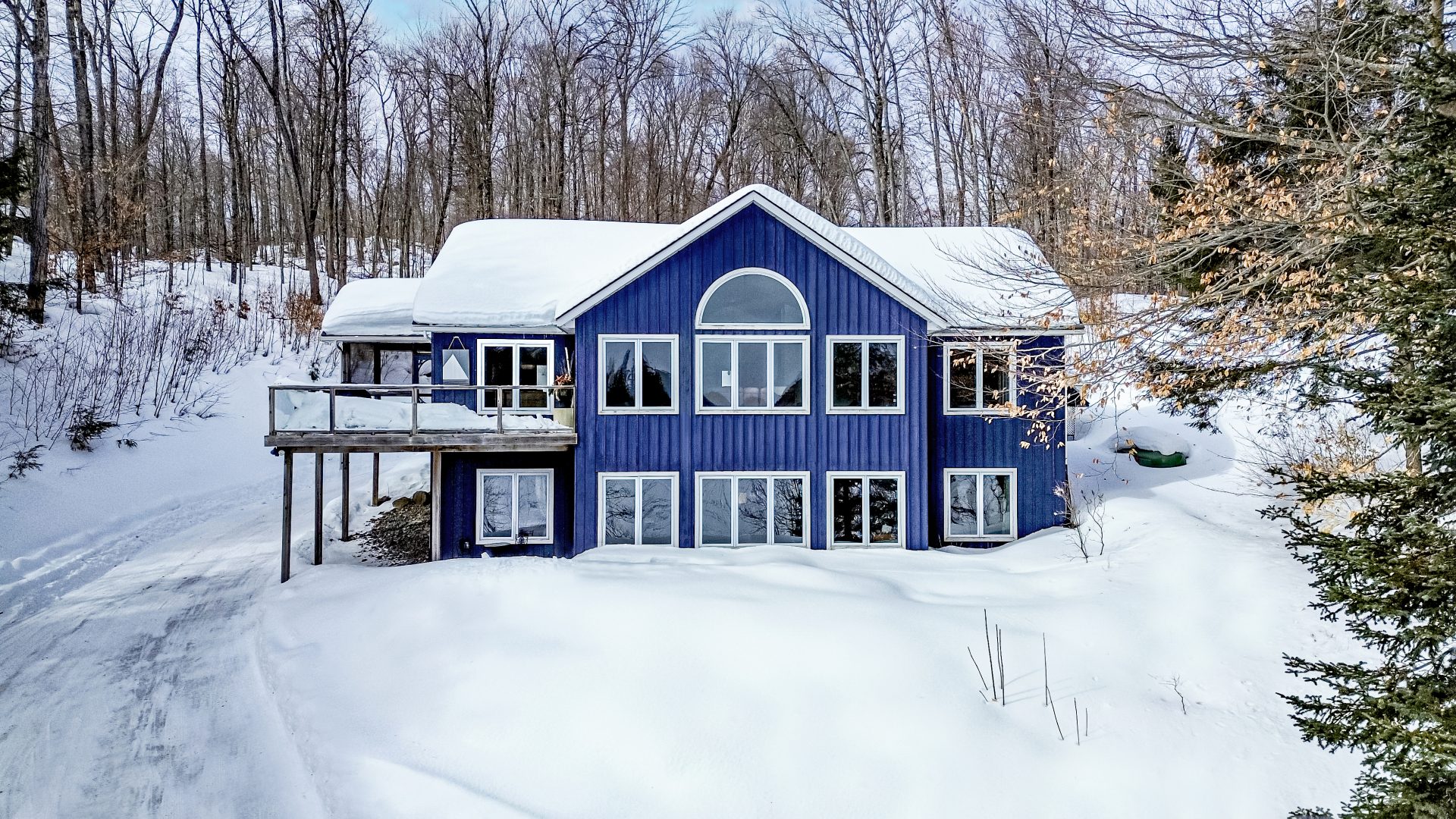A blue two-story cottage surrounded by white snow