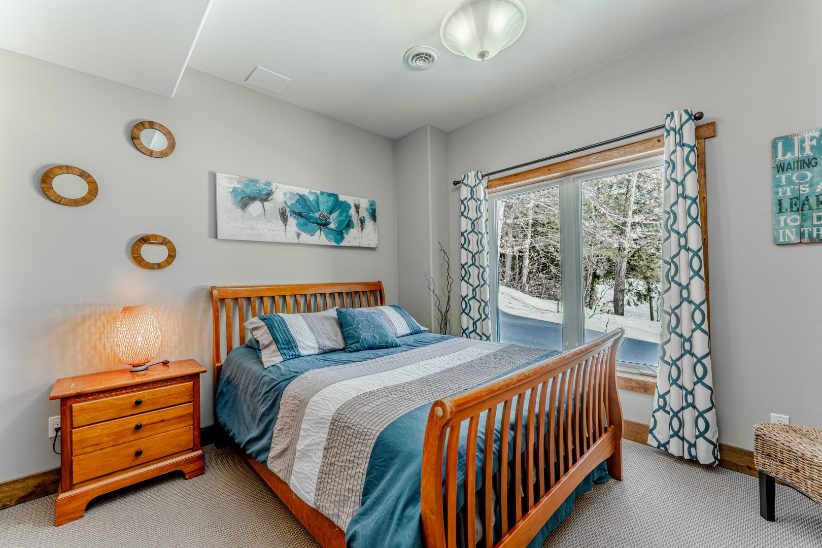 A blue bed on a wood bed frame in a white bedroom