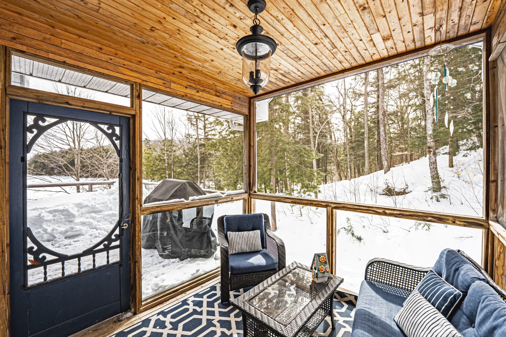 A small seating area with a glass table in a screened-in porch
