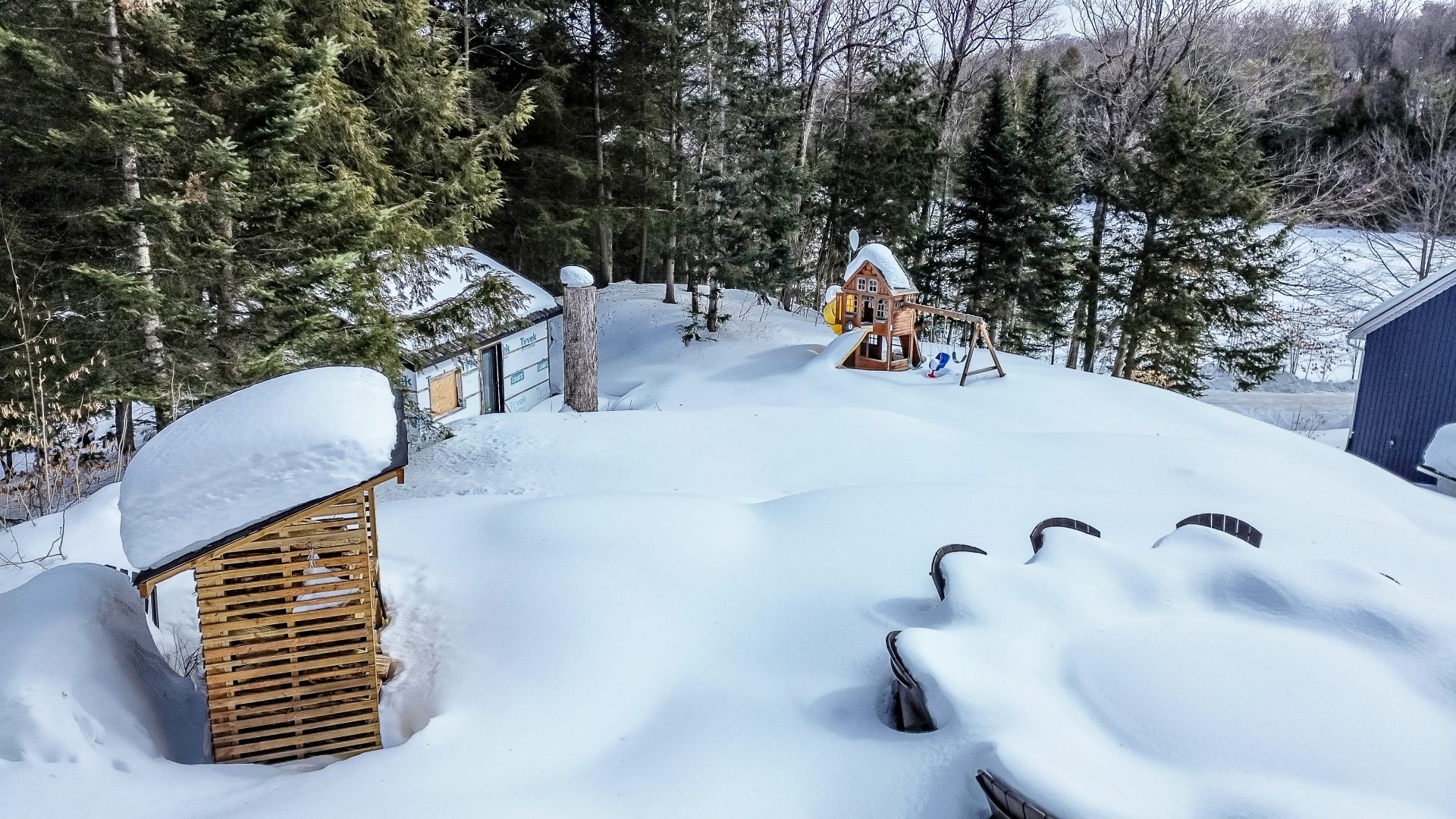 Under a thick blanket of a snow, a bunkie and playground are visible