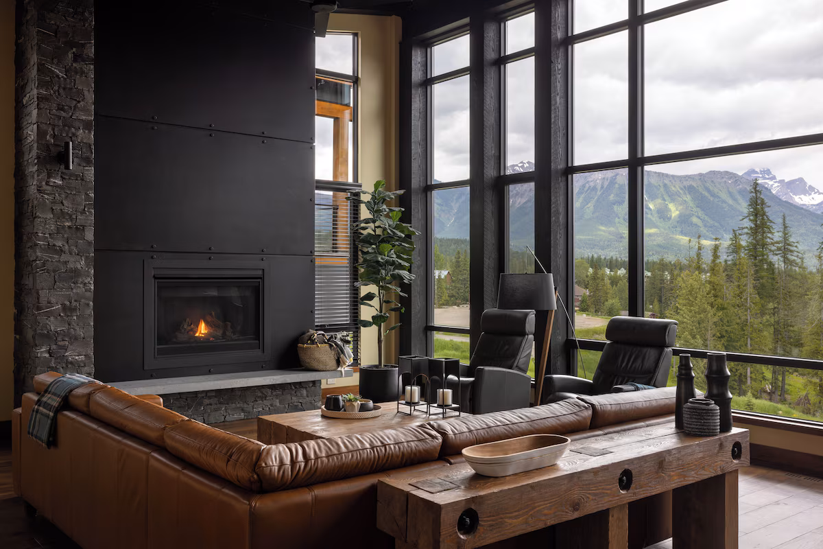 Living room of Nordic-inspired mountain home. The picture shows floor-to-ceiling windows, a brown leather couch, and TV