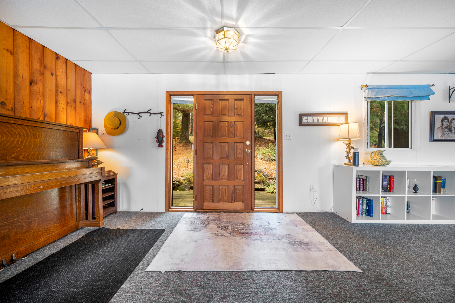 A white entryway with a brown door framed by windows and a small white rug