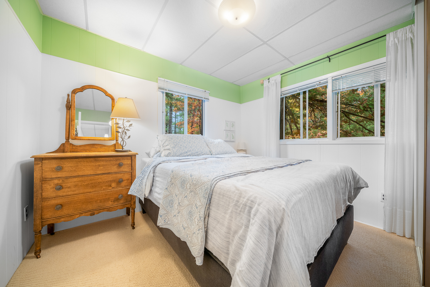A white bed in a white bedroom with lime trim around the ceiling