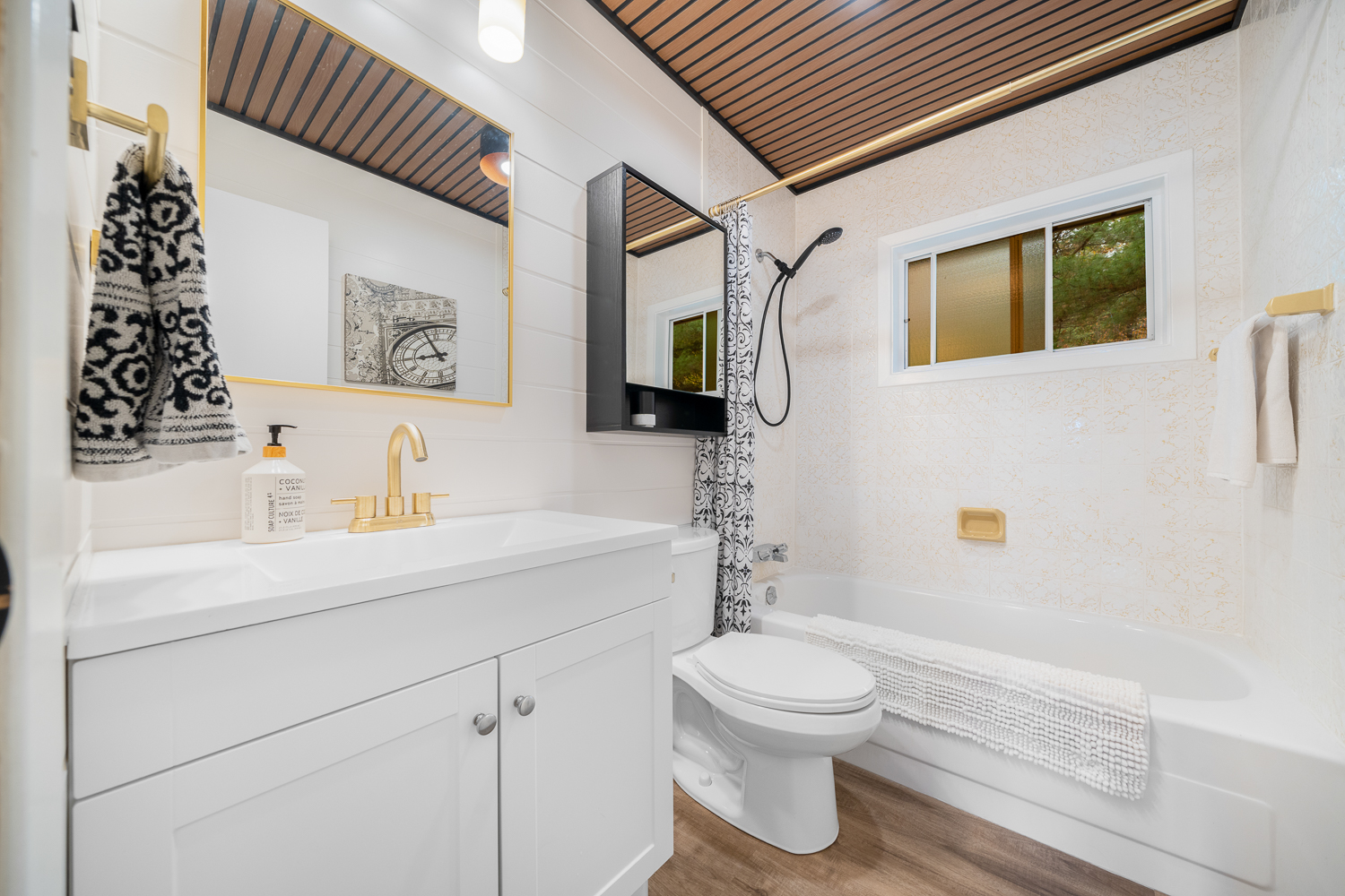 A white bathroom with a white vanity next to the toilet and shower