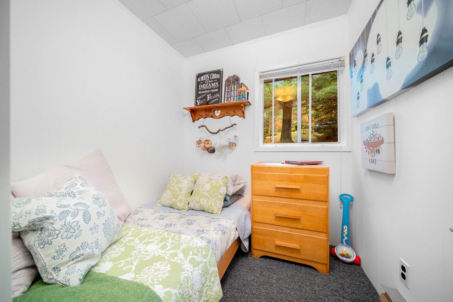 A small bed with a green cover in a small white room