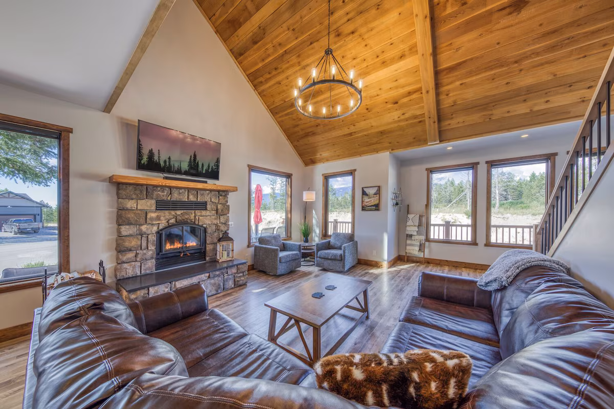 Living room of the serene mountain cabin. The photo showcases brown leather couches and a fireplace