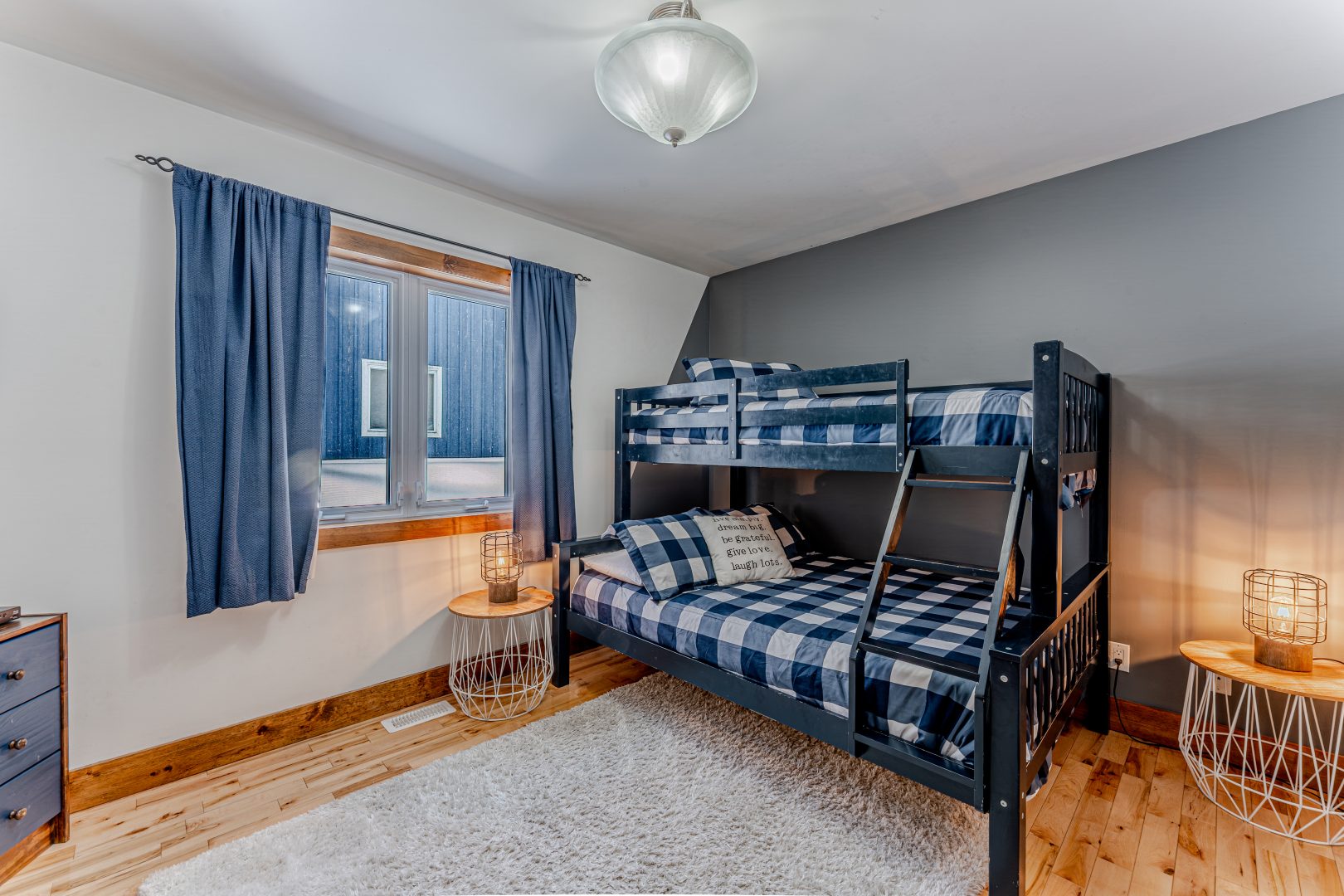Blue checked bunk beds on a dark bed frame in a white and grey bedroom