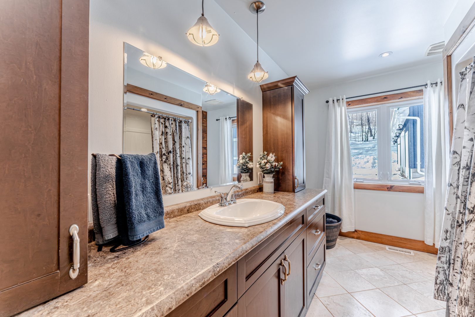 A long dark wood vanity along the wall with a large mirror hanging above