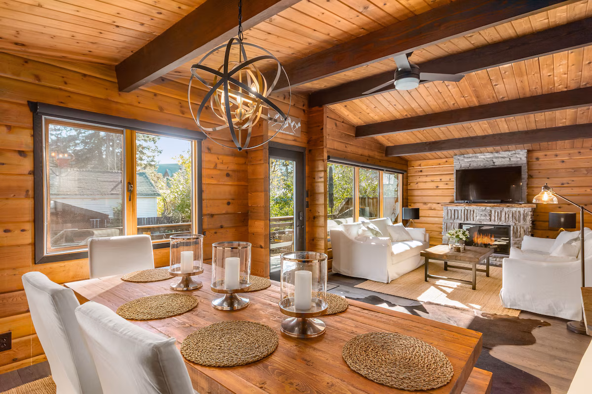 Living room of rustic mountain home in Banff. The room has wood interiors and showcases a dining table as well as a couch seating area.