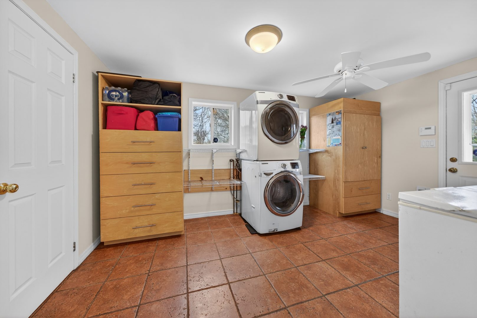 Stacked white washing machines in between light wood cabinets