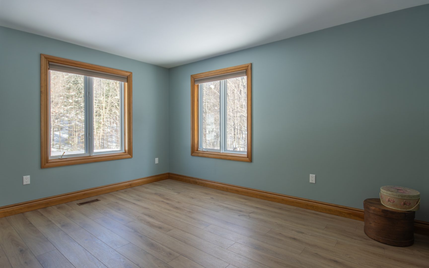 A light blue bedroom with wood-framed windows