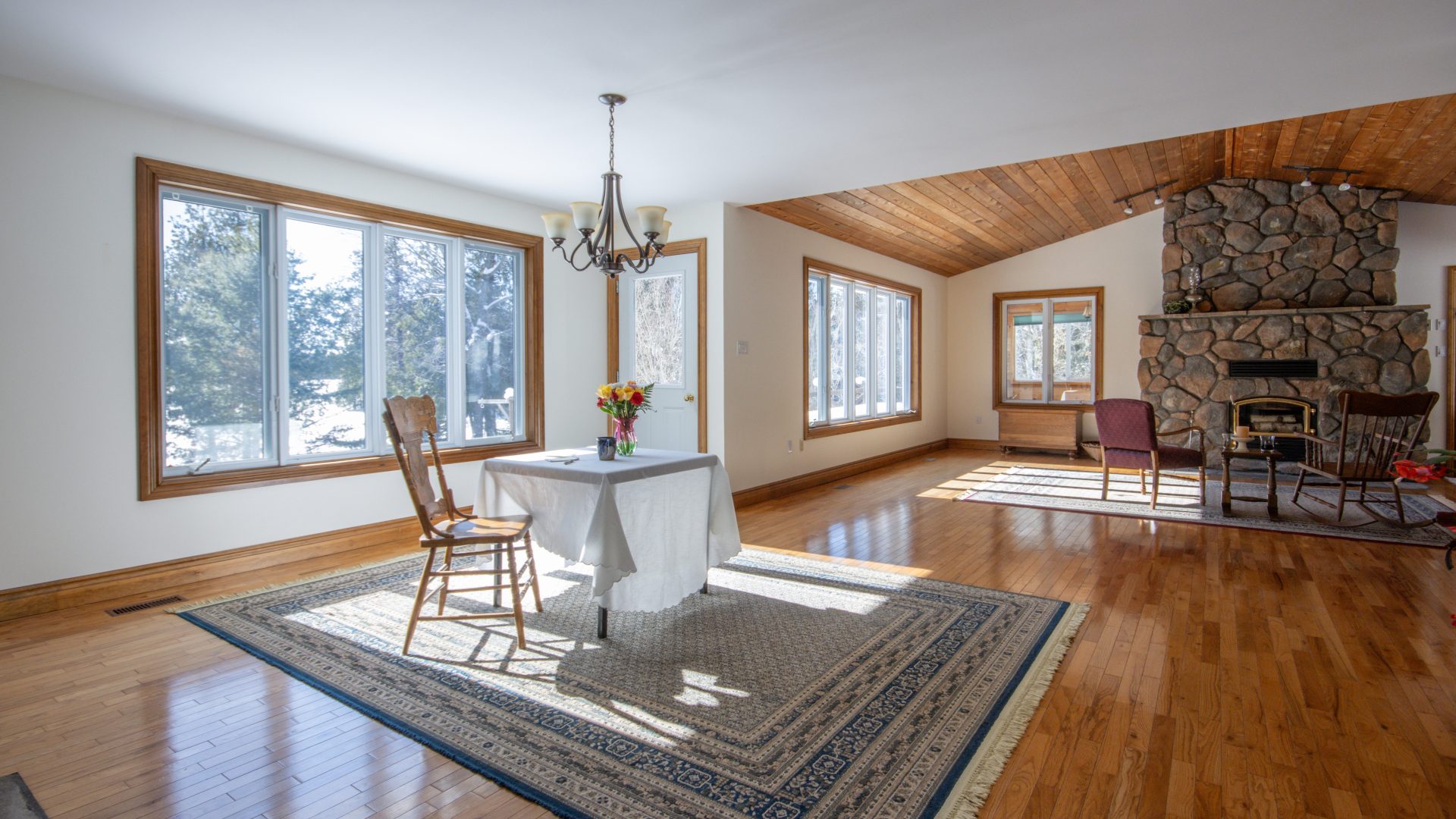 A small dining table on a grey carpet in a bright dining room