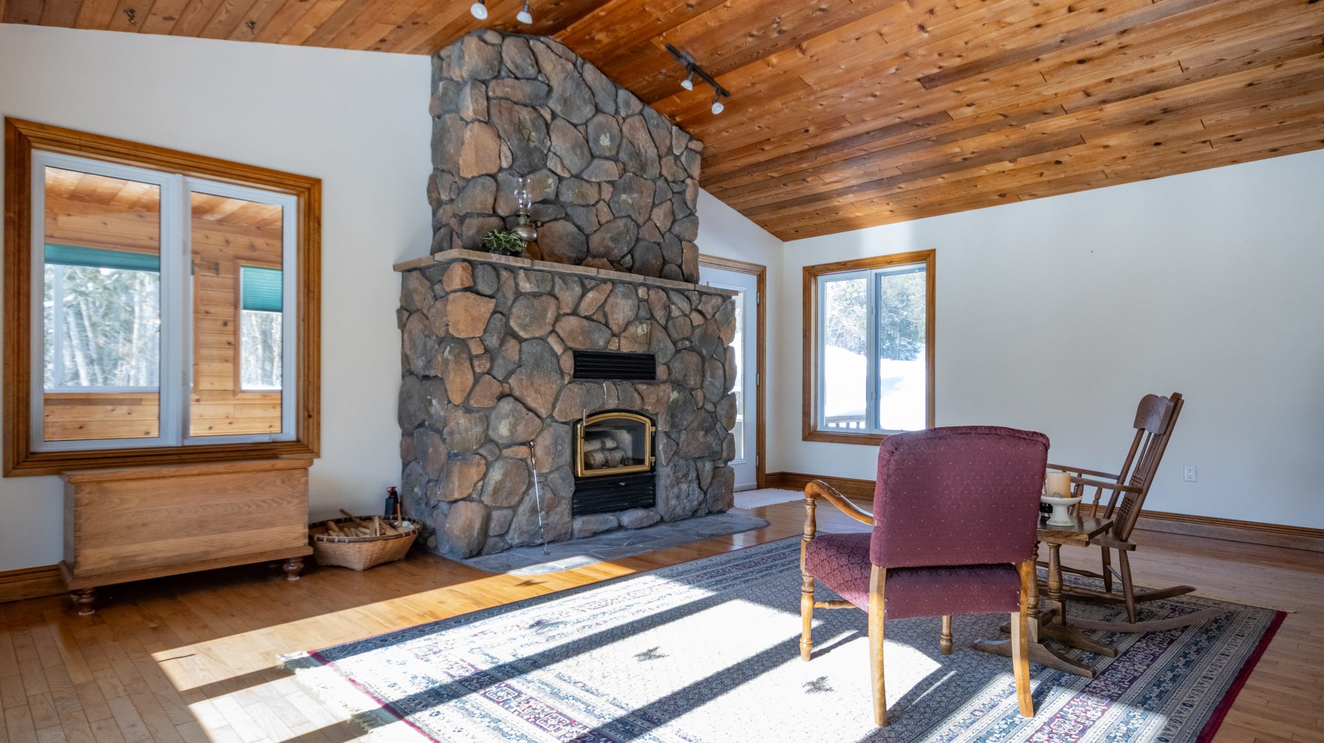 A stone fireplace in a living room with wood cathedral ceilings