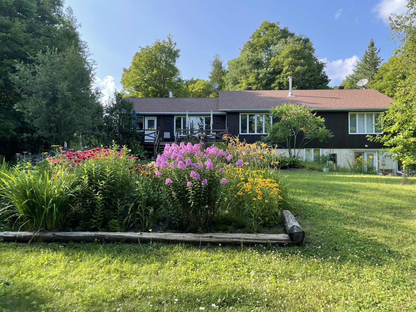A bungalow set back on a grassy property with a flower garden