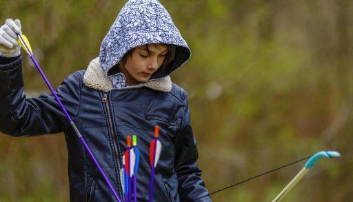 A boy holding arrows at an archery range