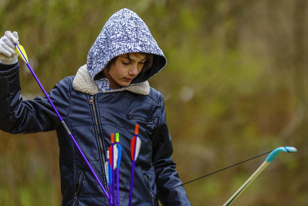 A boy holding arrows at an archery range