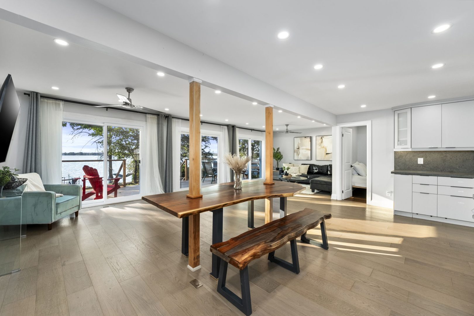A rectangular wood dining table with a wood bench in a white open-concept living area
