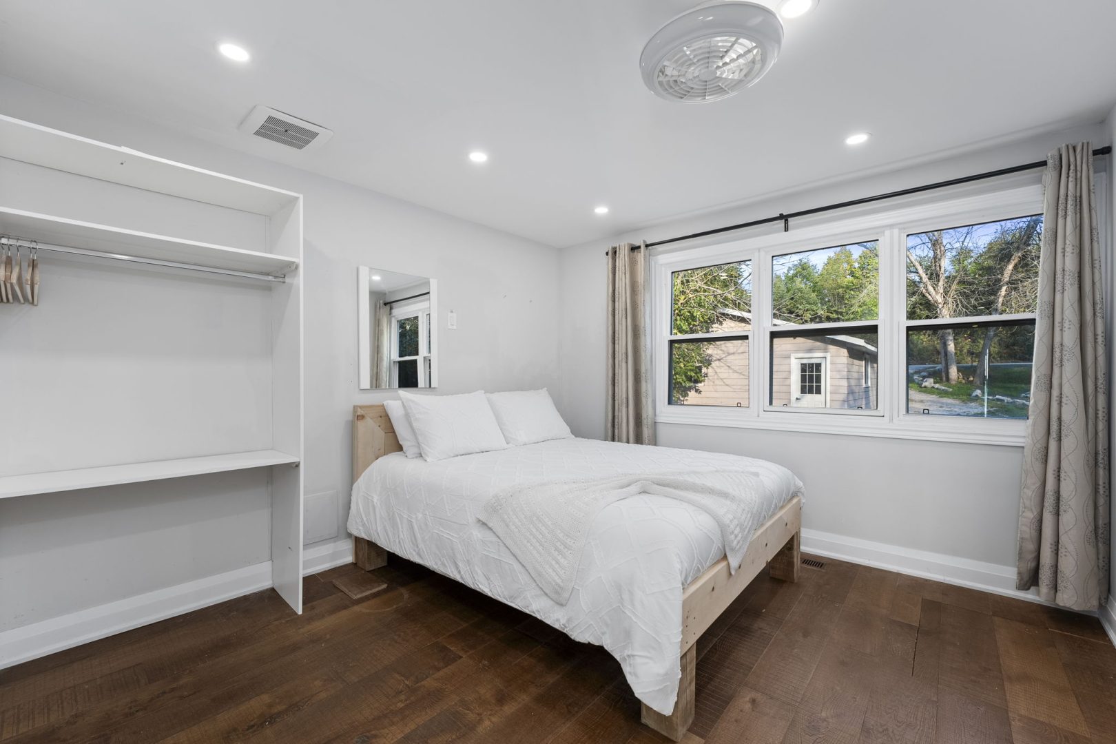 A white bed in a white bedroom with bright windows