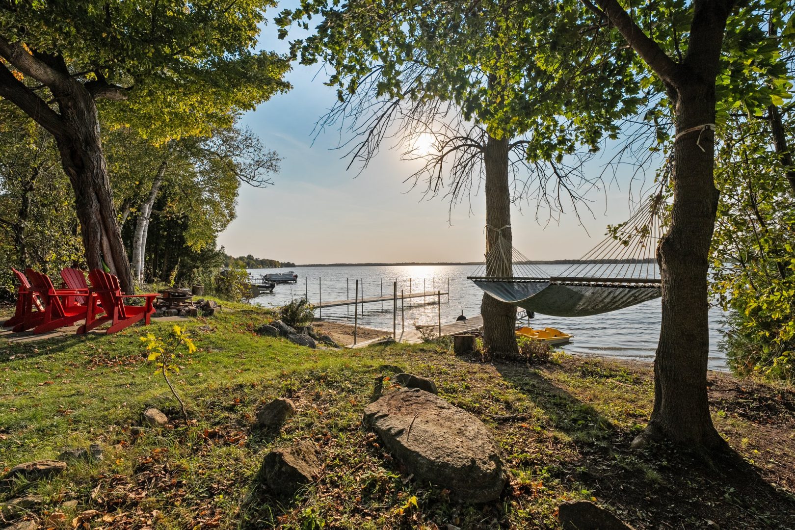 A grassy property with a hammock strung up between trees on the water