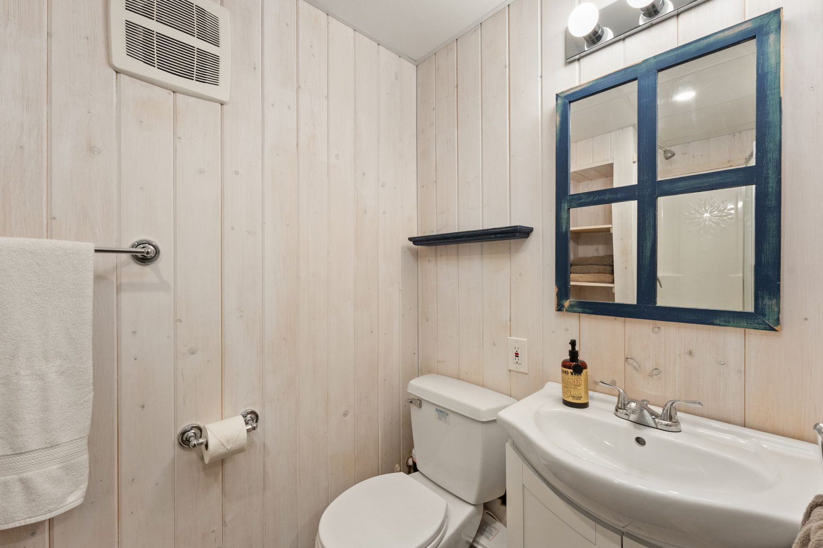 A white bathroom with paneled walls and white appliances