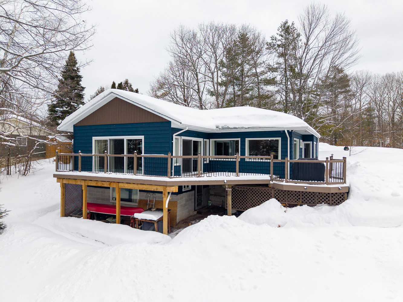 A snow-covered blue bungalow with a lower level walk-out