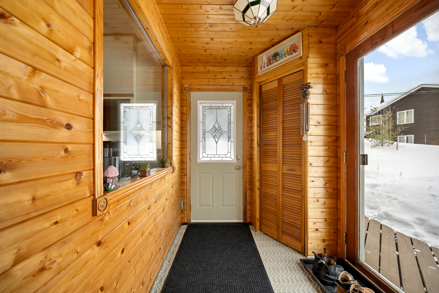 A beige front door at the end of a narrow wood-clad entryway