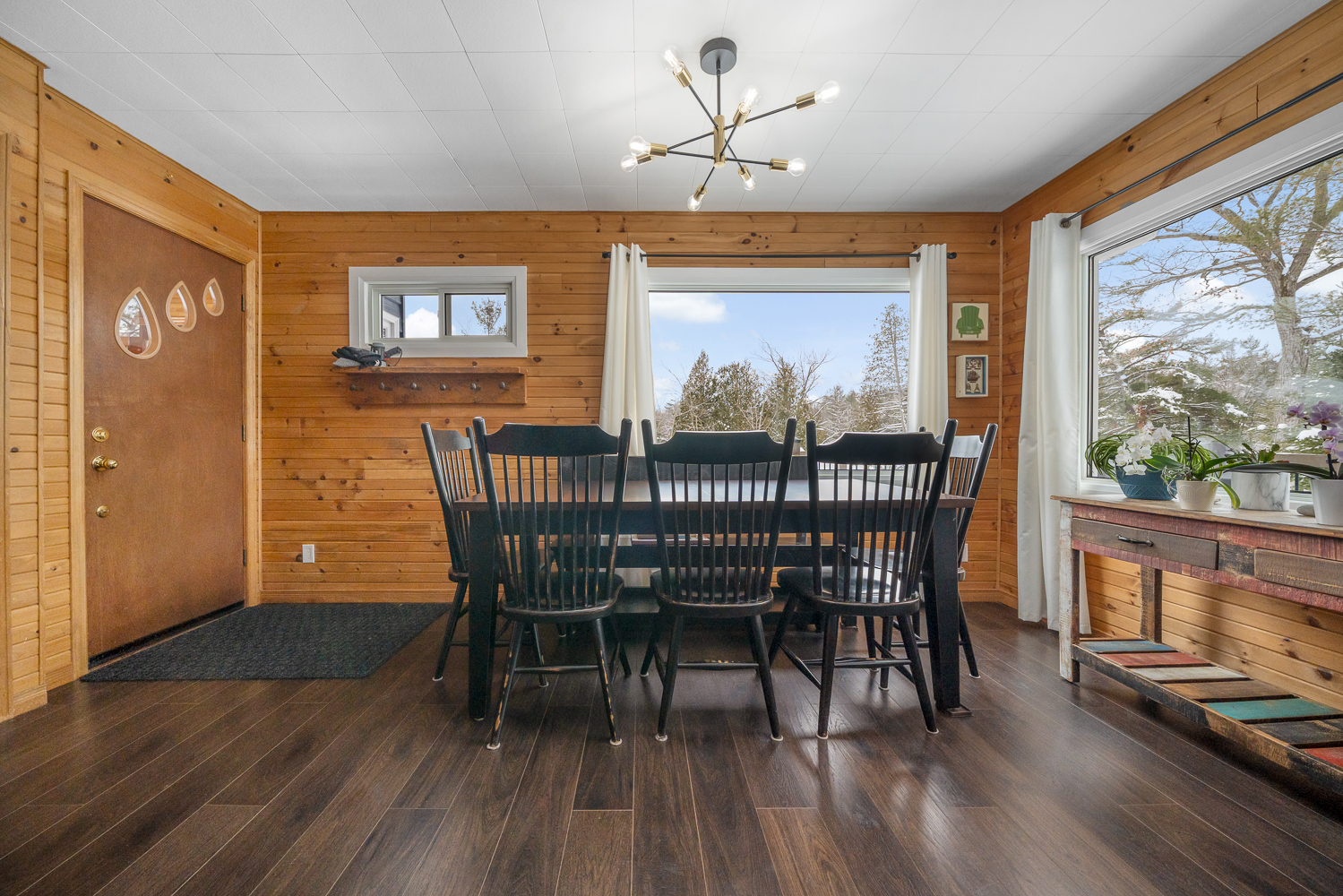 A dark wood dining table with chairs in a wood-clad room