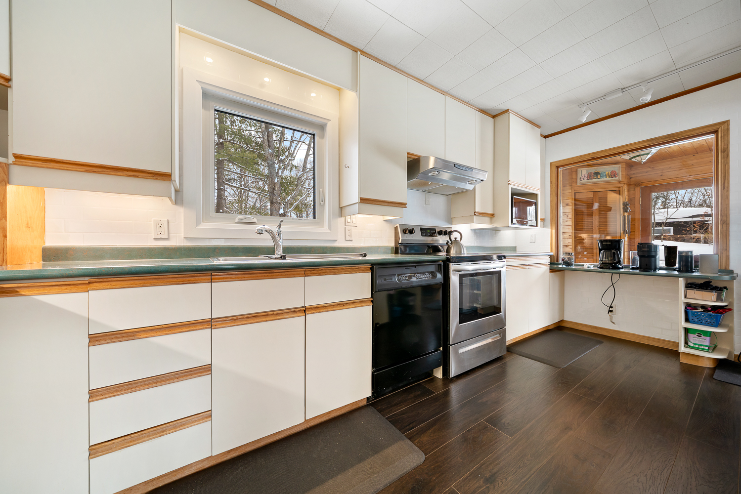 A white kitchen with light wood trim and stainless steel appliances