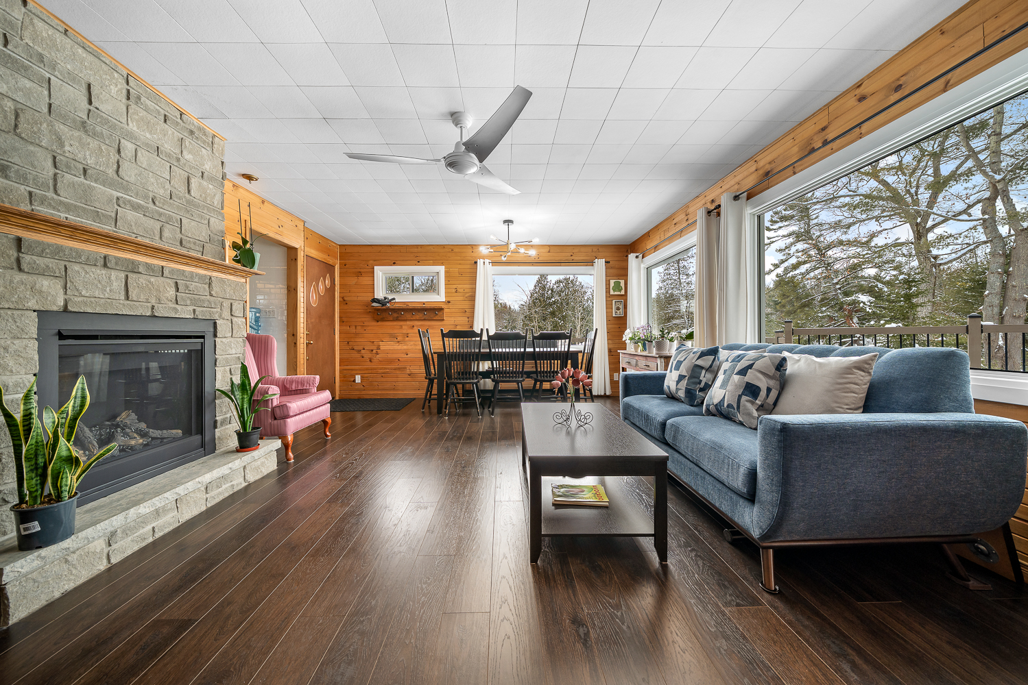 A light blue couch against a wall of windows faces a stone fireplace