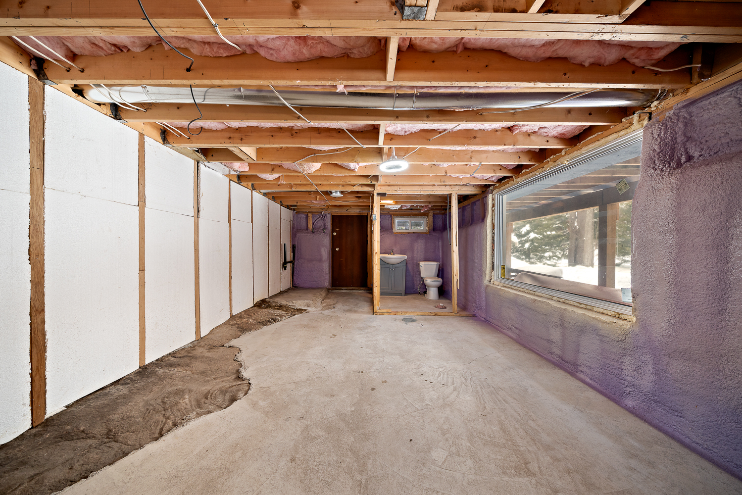 An unfinished basement with a bathroom in the back