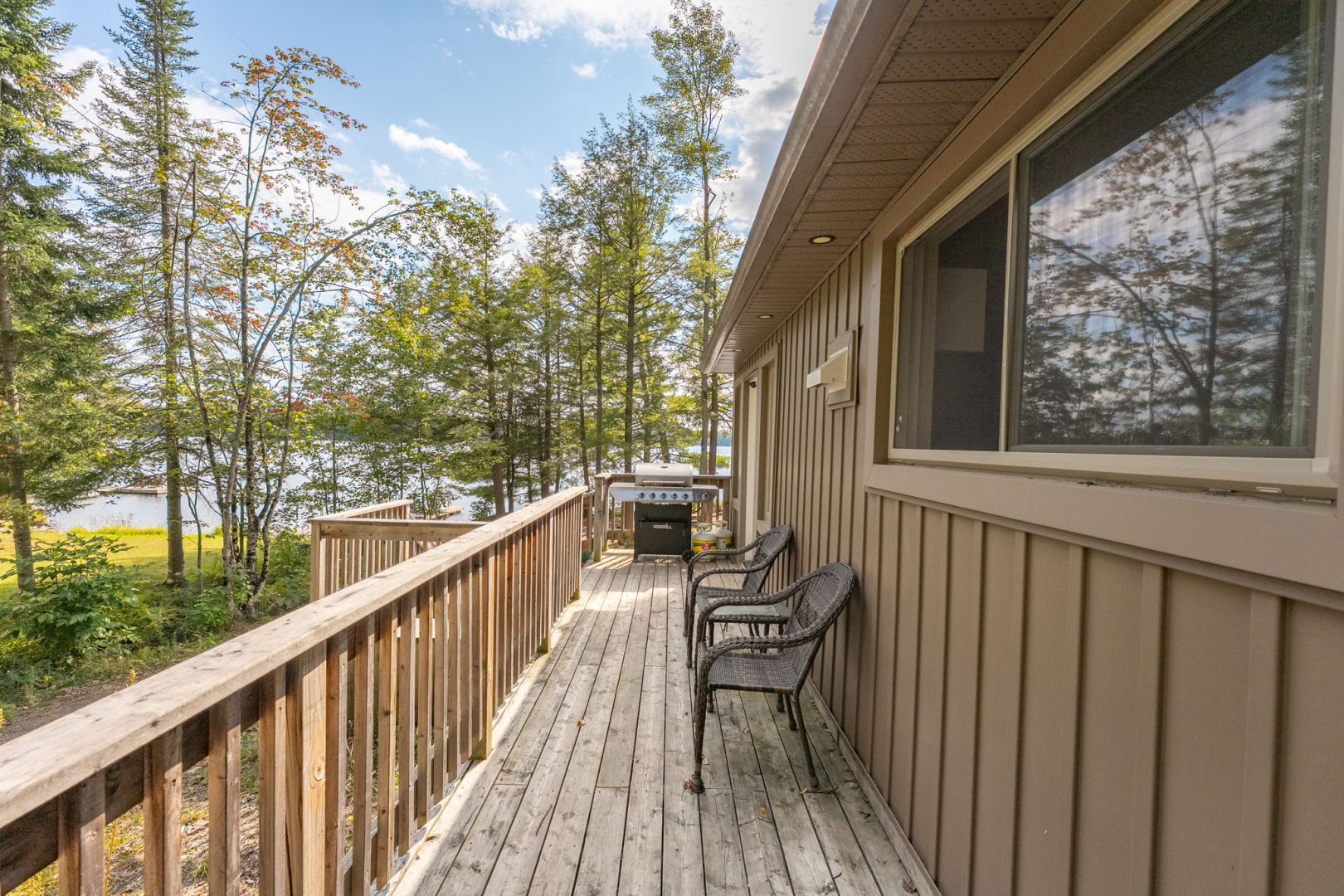 A brown cottage with a narrow deck facing the water