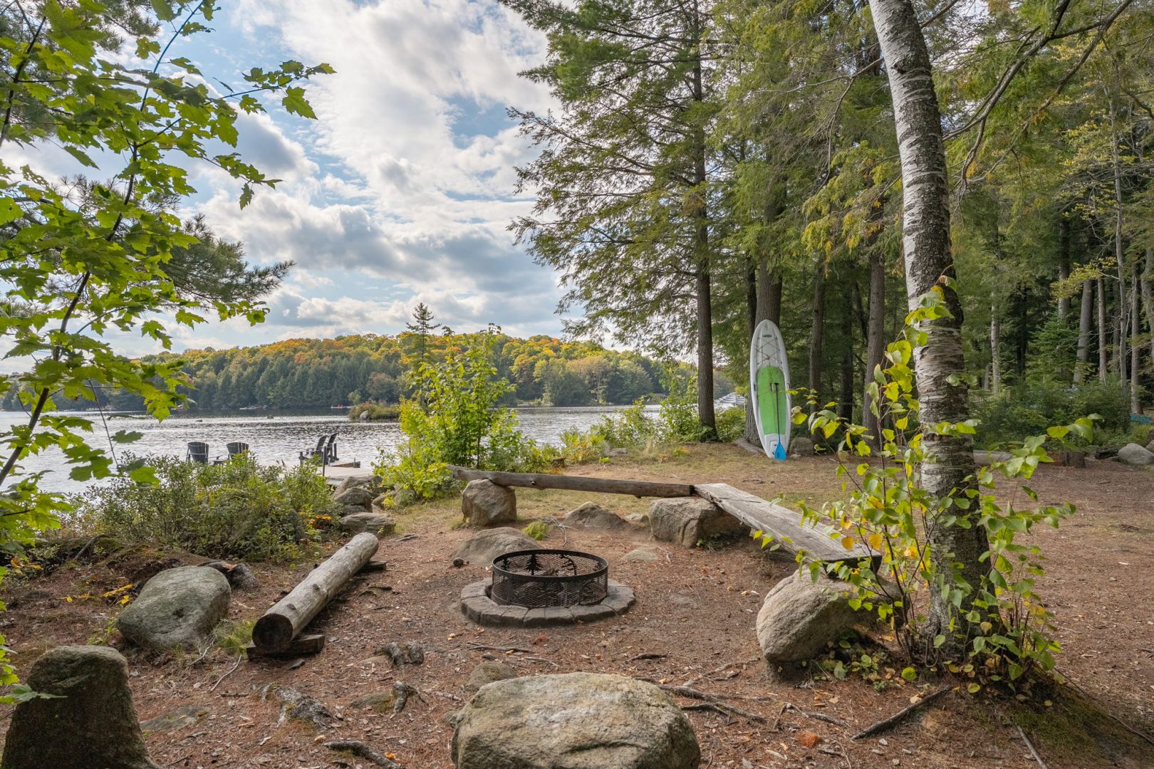 A round fire pit area with log seating next to the lake