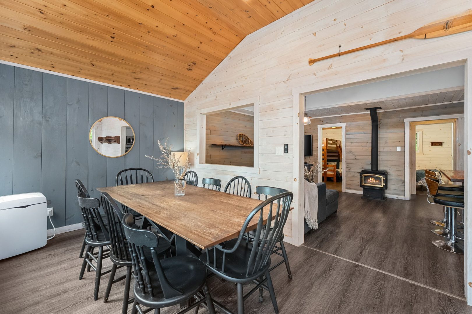 A wood table with dark grey wood chairs in a white and grey paneled dining room