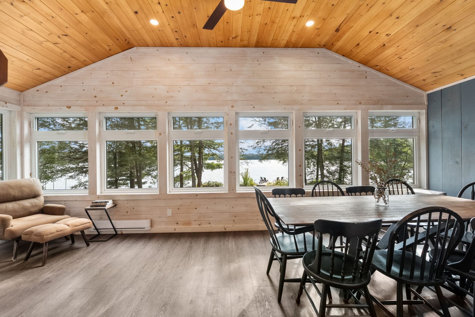 A dining table next to a wood wall with bright windows
