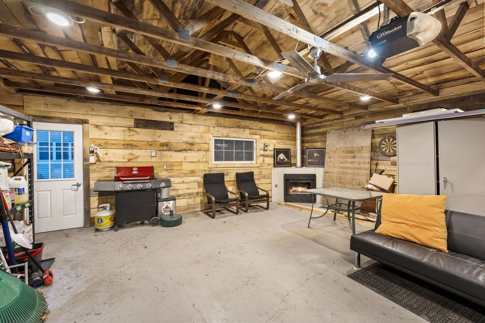A garage interior with wood walls and a fireplace tucked in the corner