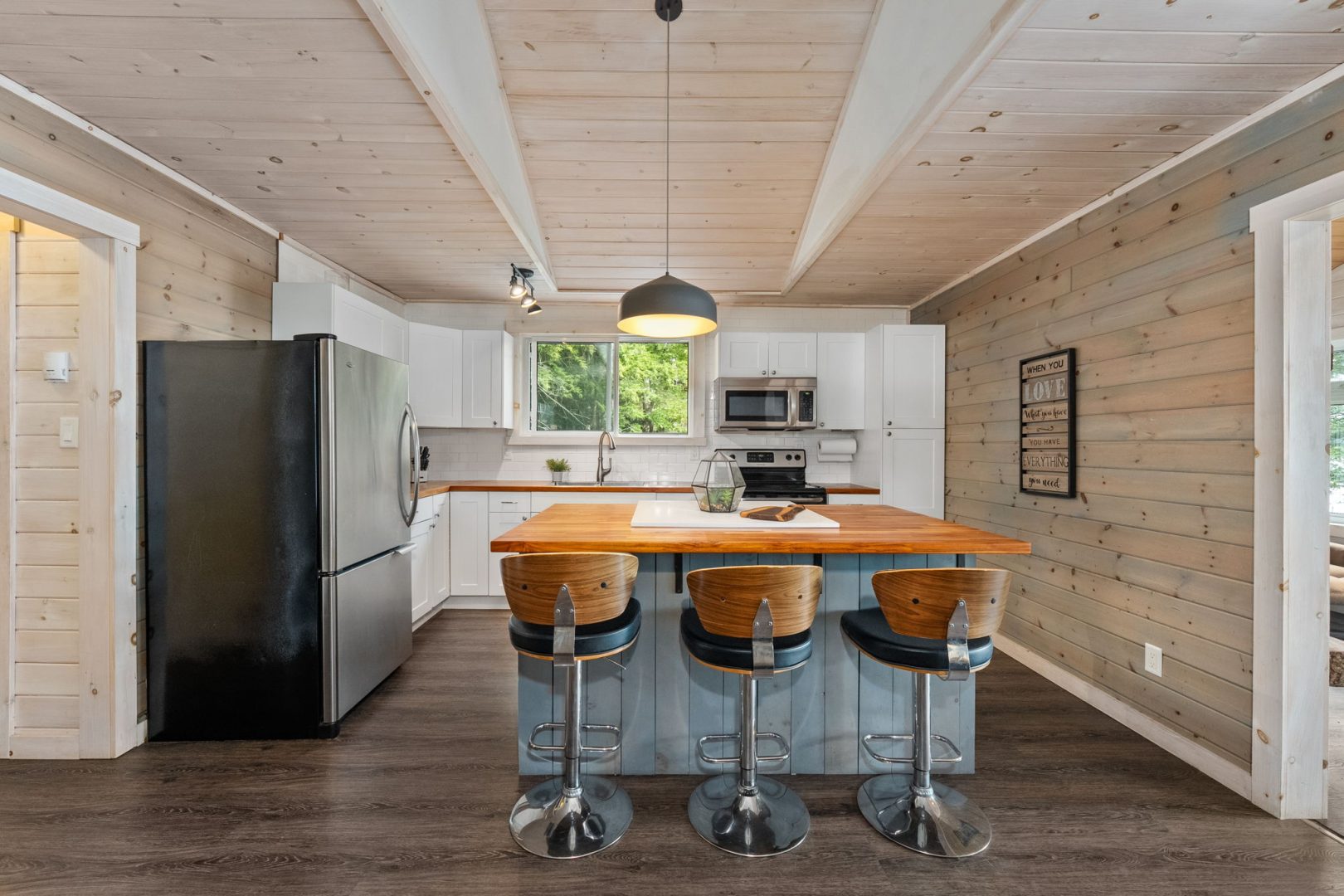 A grey kitchen island with brown leather high-top chairs in a beige kitchen