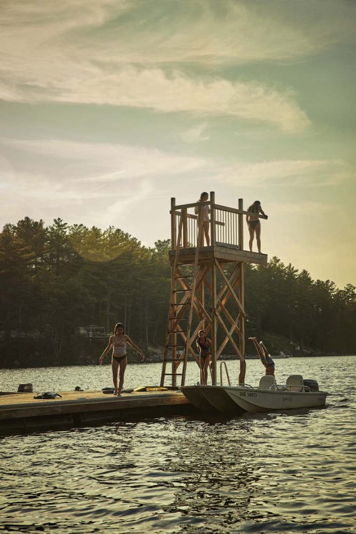 Kids getting ready to jump into a lake from a wooden dive tower