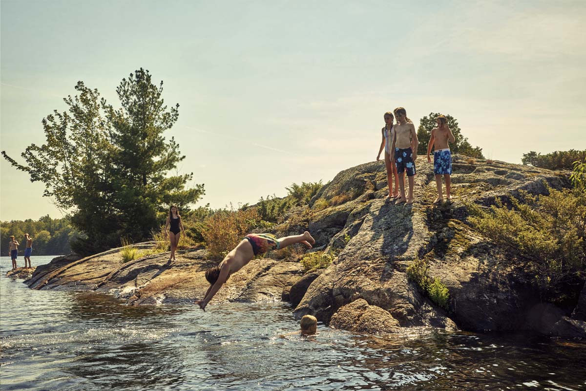 Kids diving from a small rocky hill