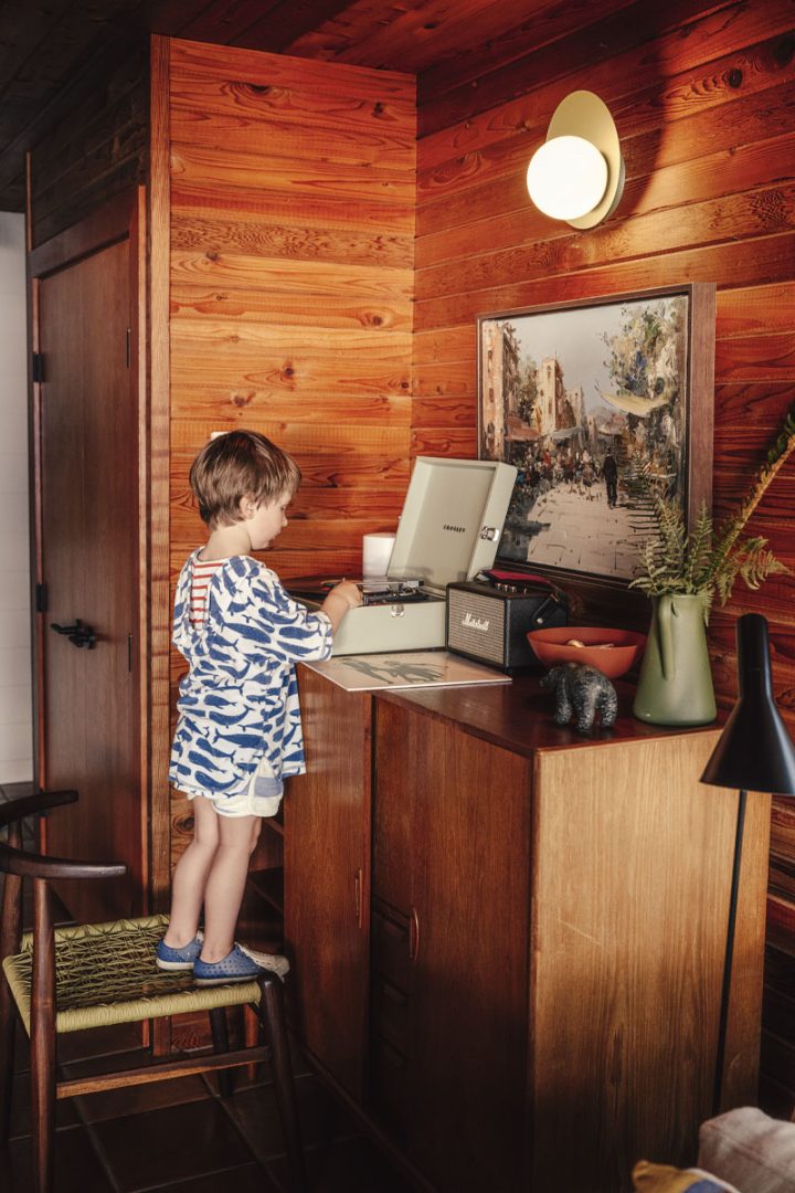 Child standing on a chair while he looks at a record player