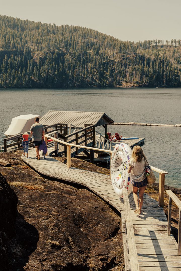 A family holding a floatie and bags while they walk to their dock