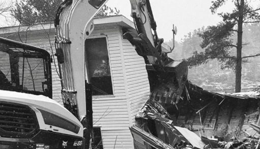 A cottage being demolished by an excavator