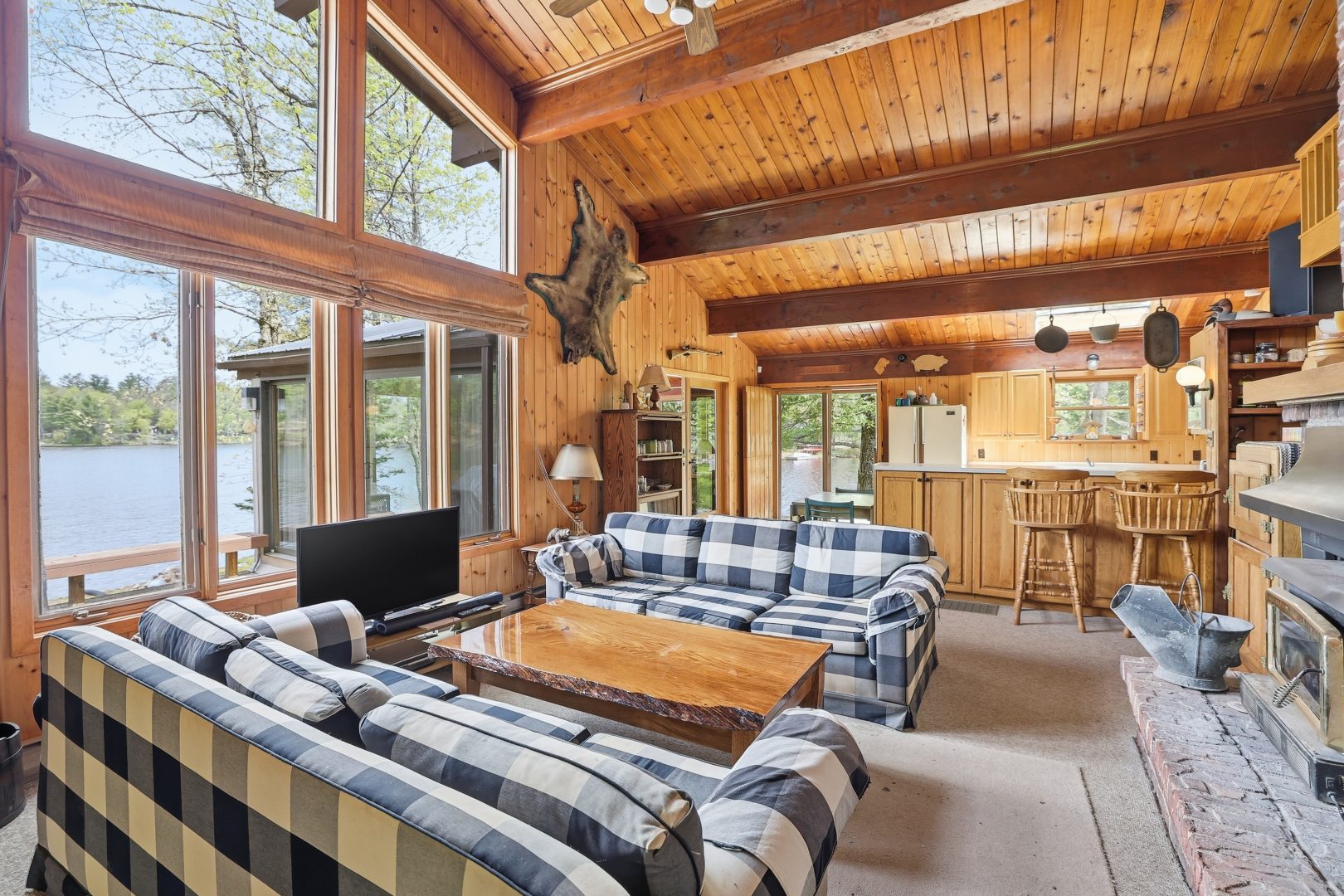 Blue and white plaid couches in an open living area. To the left, huge windows face the deck