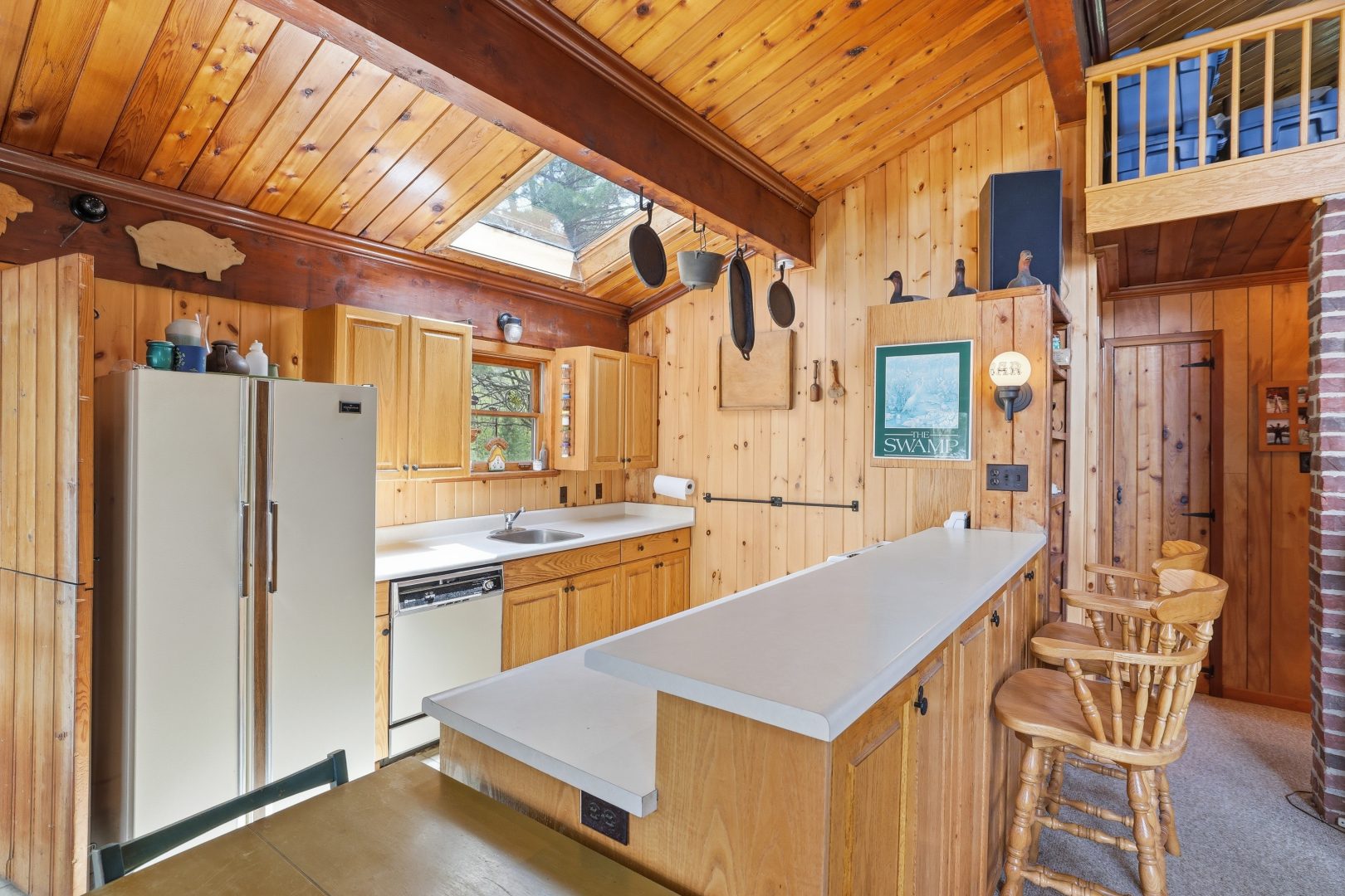 A wood-panelled kitchen with white appliances and a high-top sitting area